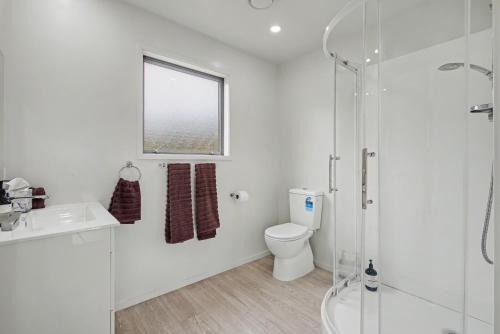 a white bathroom with a toilet and a shower at The Little Hive in Westport