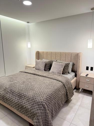 a bedroom with a large bed with a gray blanket at Adagio Quito Suite de Lujo in Quito