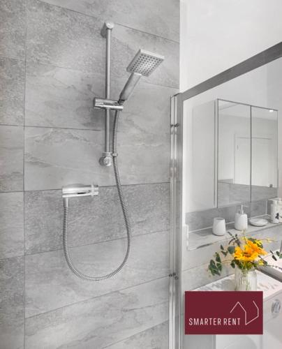 a shower with a shower head in a bathroom at High Wycombe - Garden Parking 2Bed in Buckinghamshire