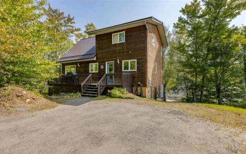 a large wooden house on a hill with a driveway at The Beaver Den in Haliburton