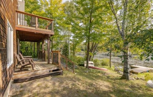 a porch of a house with a deck and trees at The Beaver Den in Haliburton