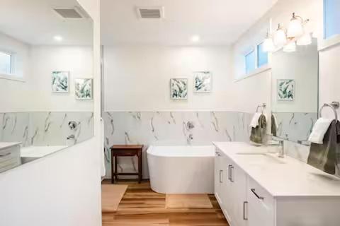 a white bathroom with a tub and two sinks and a bath tub at Harbourview Hideaway Sooke in Sooke