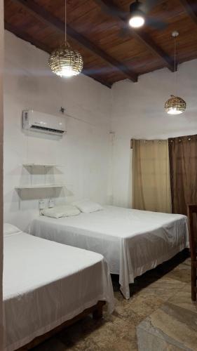 two beds in a room with white walls and two lights at Casa Esmeralda in La Huerta