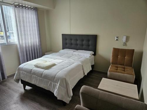 a bedroom with a large bed and a chair at Hostal Plaza Grau in Lima
