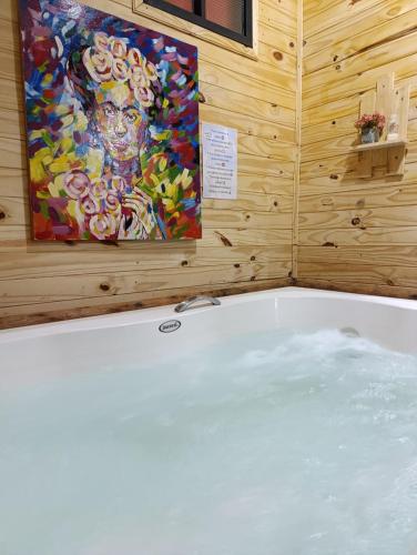 a bath tub in a room with a painting on the wall at Posada Turística Alpinas Kamba in Paraguarí