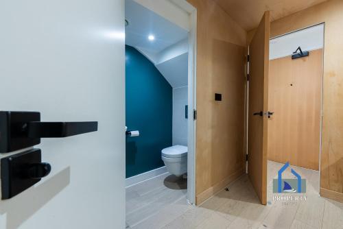 a bathroom with a toilet and a blue wall at Central Manchester Duplex - Balcony - Roof Terrace - Parking in Manchester
