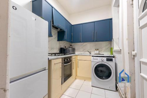 a kitchen with blue cabinets and a washing machine at Traditional Central Home-Games Room-Free Parking in Manchester