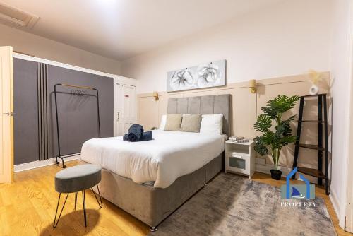 a bedroom with a large white bed and a stool at Traditional Central Home-Games Room-Free Parking in Manchester