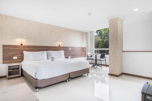 a bedroom with a large bed and a balcony at Hotel Estancia Chipichape Cali in Cali