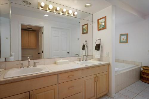 a bathroom with two sinks and a large mirror at Waikoloa Fairways Unit A207 Golf Ocean View 2BD 2BA in Waikoloa Village