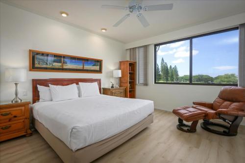 a bedroom with a bed and a chair and a window at Waikoloa Fairways Unit A207 Golf Ocean View 2BD 2BA in Waikoloa Village