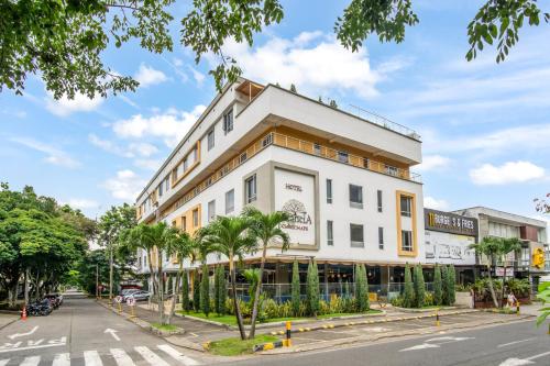 a white building with palm trees in front of a street at Hotel Estancia Chipichape Cali in Cali
