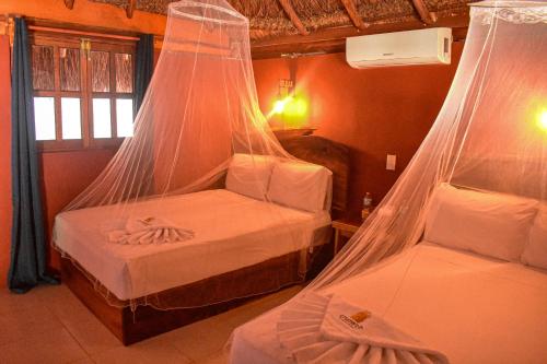 two beds in a room with mosquito nets at Hotel Aldea Cruzo'ob in Felipe Carrillo Puerto