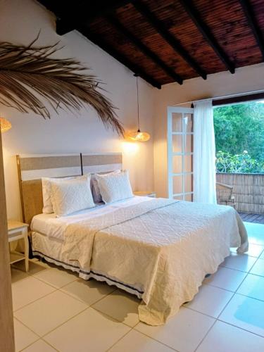 a bedroom with a bed and a large window at Palmares, Casa Rustica Suites Buzios in Búzios