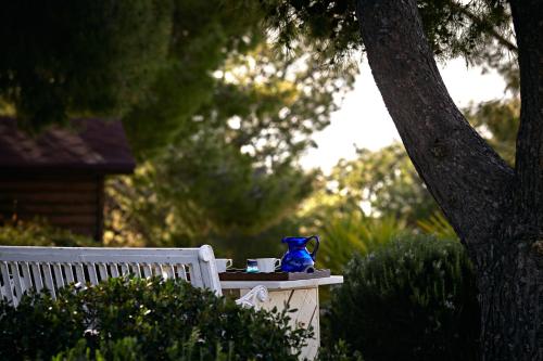 eine blaue Vase auf einem Tisch neben einer Bank in der Unterkunft Villa Irini in Porto Heli
