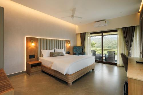 a hotel room with a bed and a balcony at Kohu By Honeyvale in Mudigere