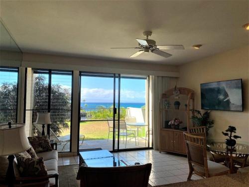 a living room with a ceiling fan and a view of the ocean at Napili Point Oceanfront Turtle View 1BR - Unit B30 condo in Lahaina