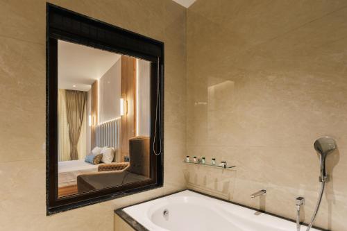 a bathroom with a tub and a large mirror at Kohu By Honeyvale in Mudigere