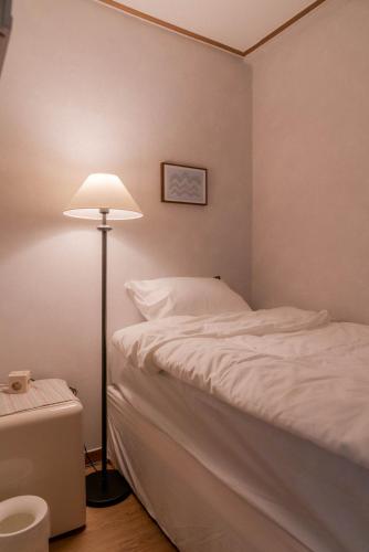 a bedroom with a white bed and a lamp at 메종드브릭 호텔 in Seoul