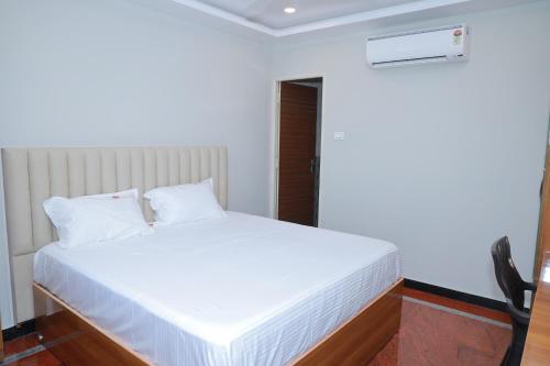 a white bed in a white room with aigiligiligil at Hotel Sivani in Kalakkādu