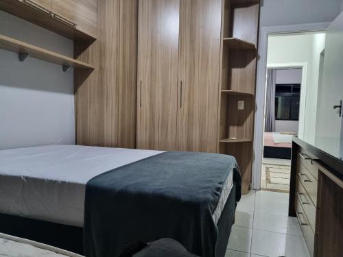 a bedroom with a bed and wooden cabinets and a television at 2-bedroom apartment in Ubá