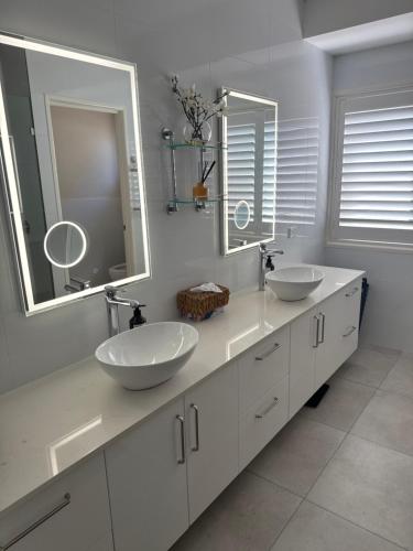 a bathroom with two sinks and two mirrors at Luxury Newport canal king suite home in Redcliffe