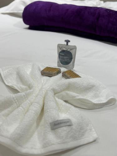 a white towel on a bed with a bottle of soap at LUXO Premium Studio Pelinca in Campos dos Goytacazes
