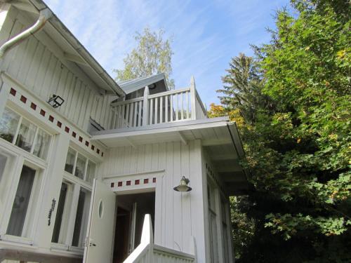 a white house with a balcony on top of it at Willa Tapala in Matildedal