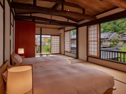 two beds in a room with windows at NIPPONIA HOTEL Takehara Saltworks Town in Takekara