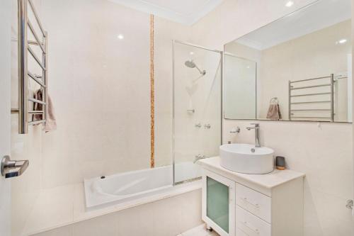 a white bathroom with a sink and a mirror at Echo Waves in Kiama