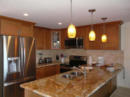 a kitchen with wooden cabinets and a stainless steel refrigerator at Peaceful Ocean-View 2BR Loft Escape - Unit C38 condo in Lahaina