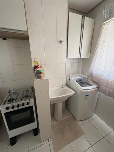 a small white kitchen with a sink and a stove at Apartment in Ponta Negra in Manaus