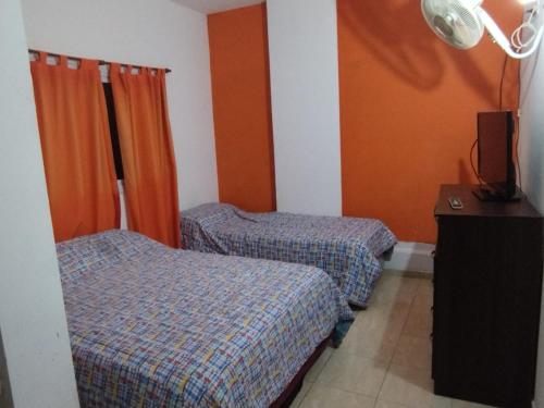 two beds in a room with orange walls at Hotel Graciela in Villa Carlos Paz