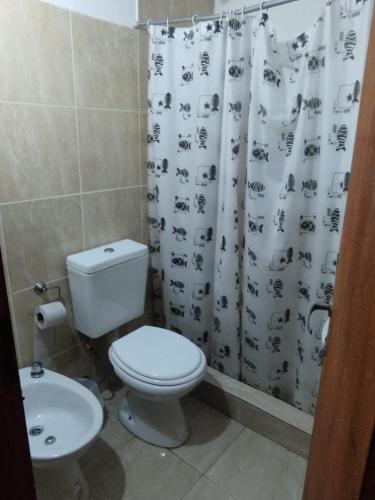 a bathroom with a toilet and a shower curtain at Hotel Graciela in Villa Carlos Paz