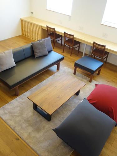 ein Wohnzimmer mit Sofa, Tisch und Stühlen in der Unterkunft Rinrei terrace 一棟貸切 シングルルーム6部屋 各部屋トイレ シャワー付 in Azumino