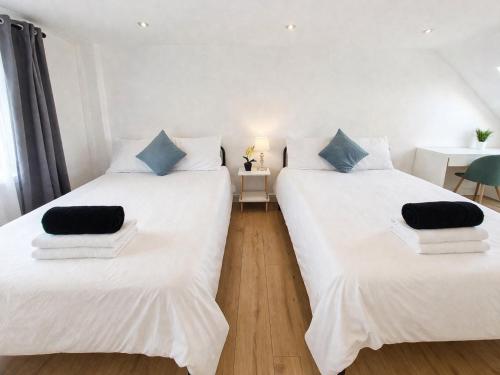 two beds in a room with white sheets and blue pillows at Victoria House - Cozy Rooms in Edmonton