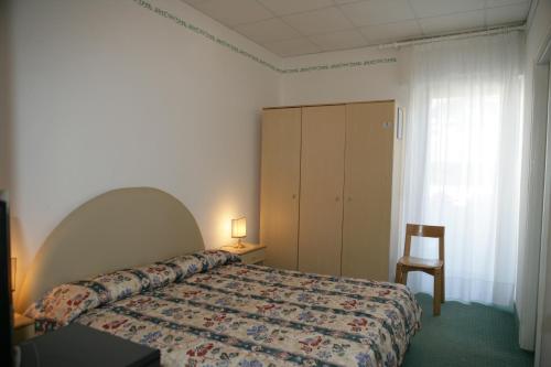 a bedroom with a bed and a chair and a cabinet at Hotel Villa Rosa in Grado