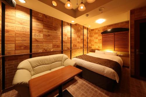 a bedroom with a bed and a couch and a table at ホテルファインシエル島根松江店 - 大人専用 in Matsue