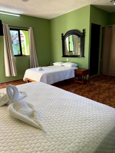 two beds in a room with green walls at Casa Xu´unan in Valladolid