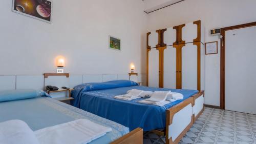 two beds in a room with blue sheets at Hotel Canasta in Misano Adriatico