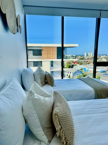 a bedroom with two beds and a large window at Sunshine Coast Paradise in Maroochydore