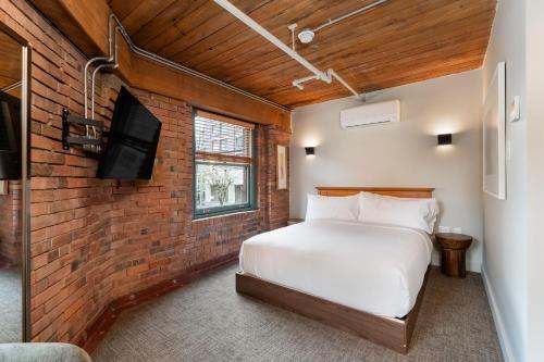 ein Schlafzimmer mit einem weißen Bett und einer Backsteinwand in der Unterkunft Block House in Vancouver