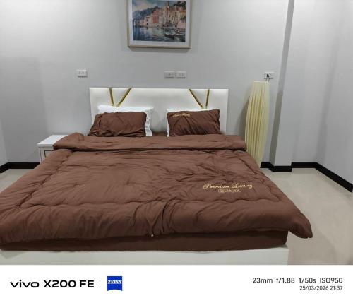 a bed with a brown blanket on top of it at Aroya Pool Villa Hatyai in Ban Thung Ri