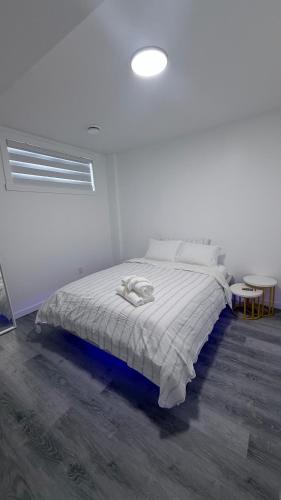 a white bedroom with a bed and a table at Private Creekstone Basement Suite with Kitchen in Calgary