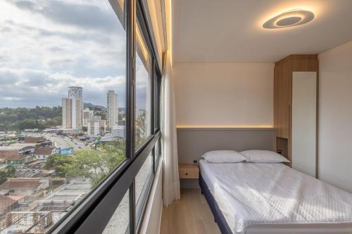 a bedroom with a bed and a large window at Edificio ON in Blumenau
