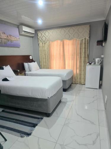 a hotel room with two beds and a television at Rainbow Guest House and Tours in Uitenhage