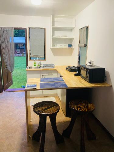a kitchen with a counter with a microwave and two stools at Huahine Serenity Cottage in Maroe