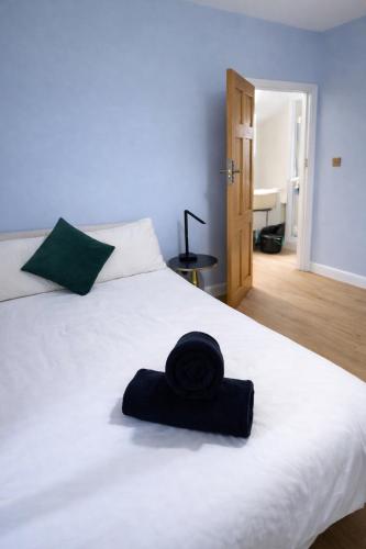 a black hat sitting on top of a white bed at Victoria House - Cozy Rooms in Edmonton