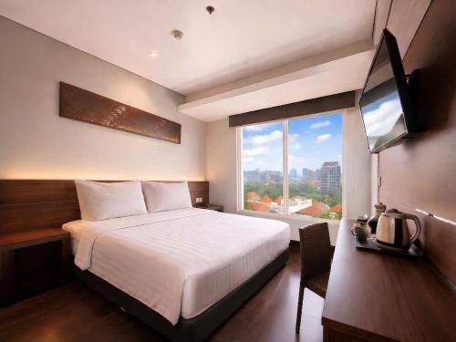 a bedroom with a bed and a large window at BATIQA Hotel Darmo - Surabaya in Surabaya