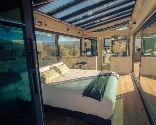 a bedroom with a bed in a house with windows at Haurapa PurePod in Cromwell